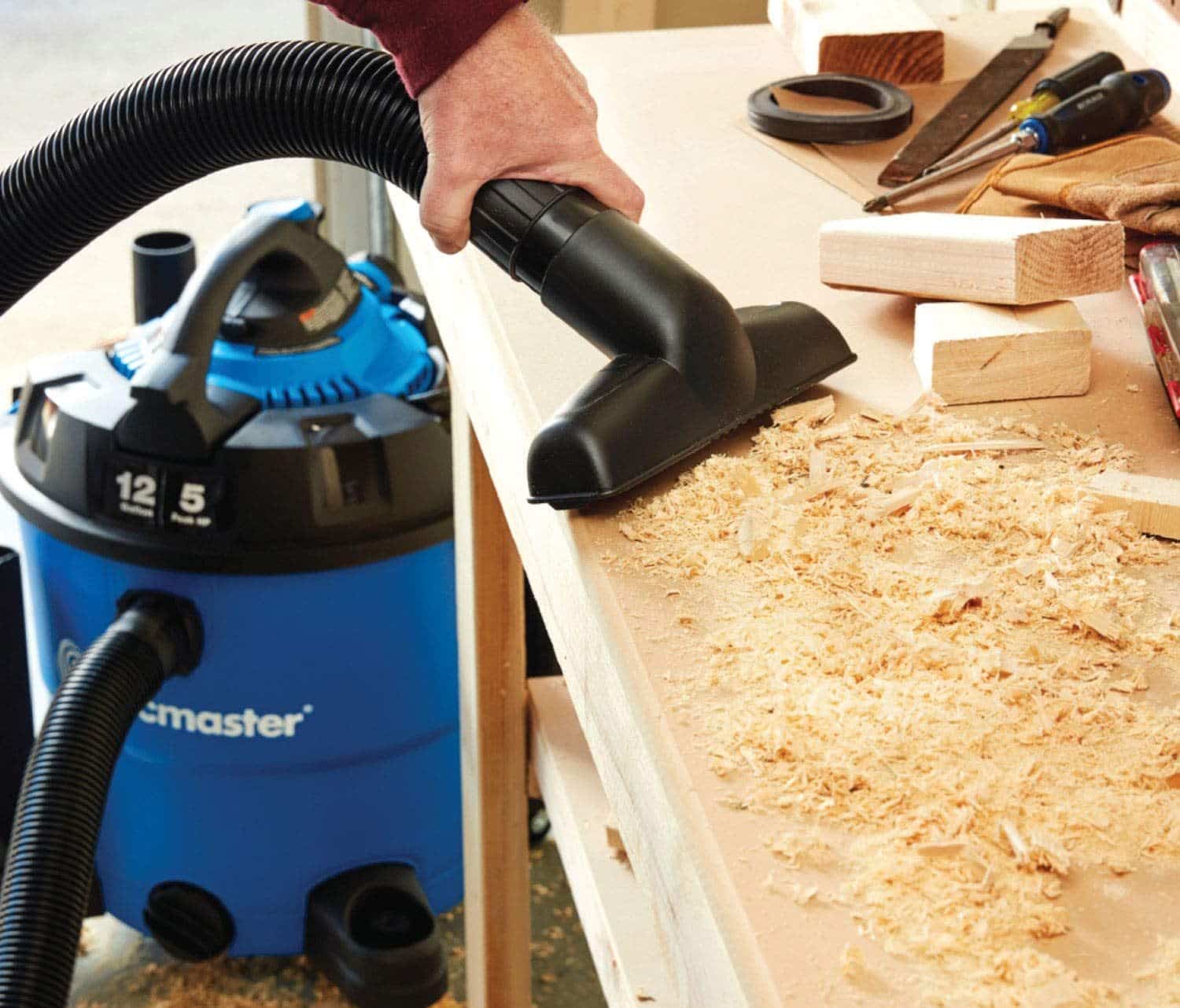 man using vacuum dust collector in wood workshop