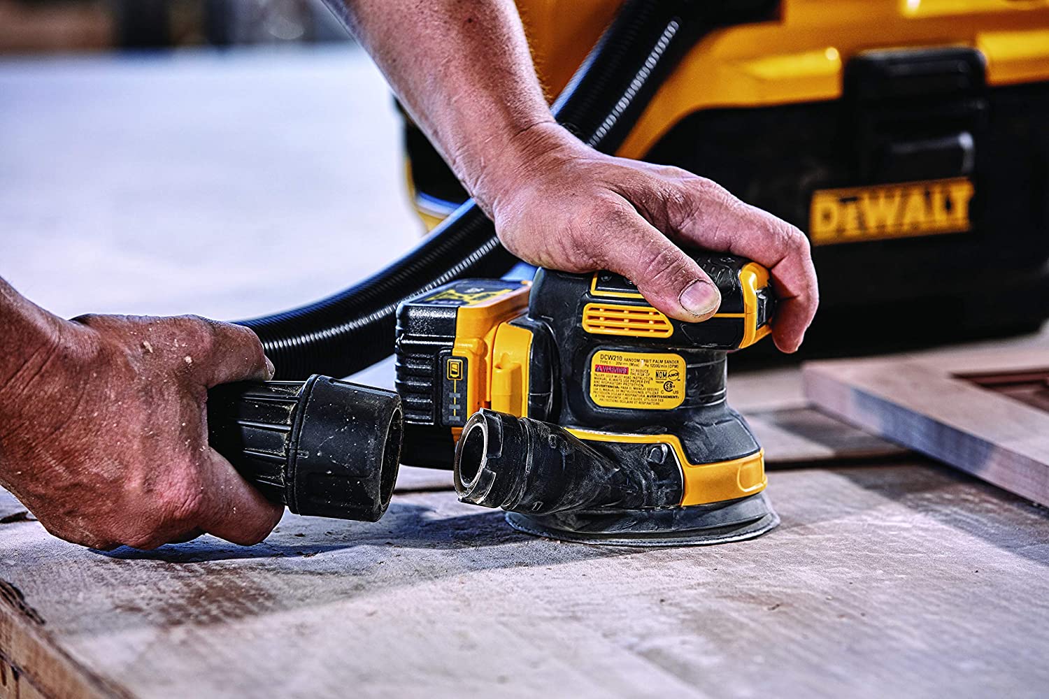 wood worker attaching exhaust pipe to rotary sander